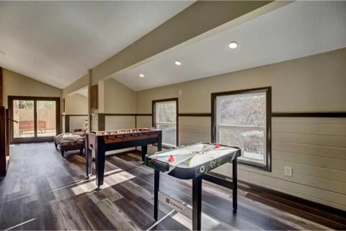 A lively interior game room with a foosball table, air hockey table, and large windows letting in natural light. The space is designed for fun, socializing, and relaxation, providing an exciting indoor retreat after days spent outdoors.