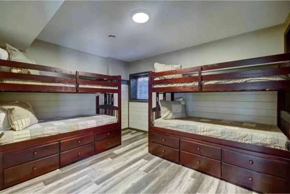A playful and comfortable bedroom scene featuring bunk beds with textured bedding and storage drawers, ideal for families or groups. The space feels both cozy and functional.