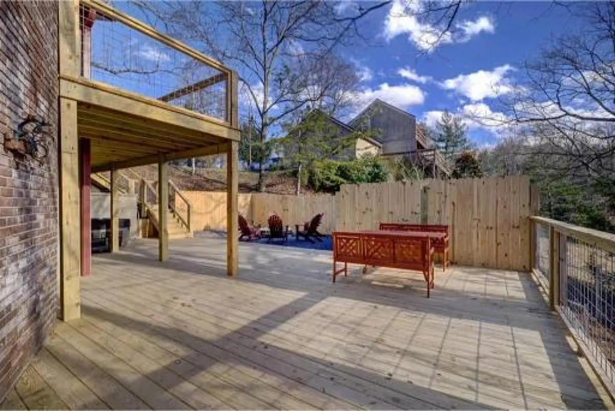 A wooden deck with outdoor seating surrounded by trees, creating a casual and welcoming space. The deck is designed for barbecuing, relaxing, and socializing, seamlessly connecting the indoors with the outdoors.