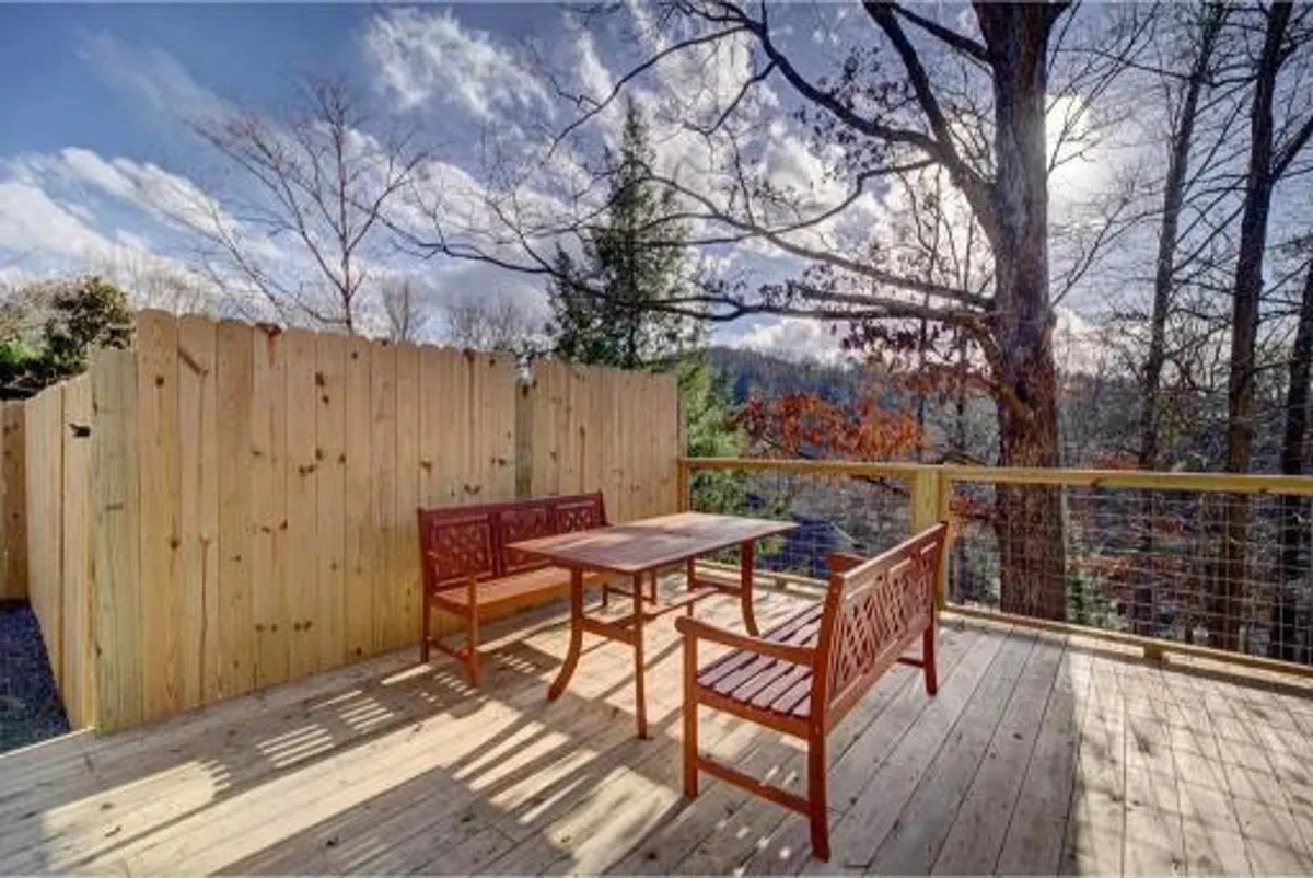 A spacious wooden deck surrounded by lush trees, featuring comfortable outdoor furniture arranged for group gatherings. The deck invites relaxation and socialization, with plenty of seating for guests and a natural backdrop that sets an inviting scene for outdoor activities. Subtle details hint at the perfect place for sunset cocktails or festive meals.