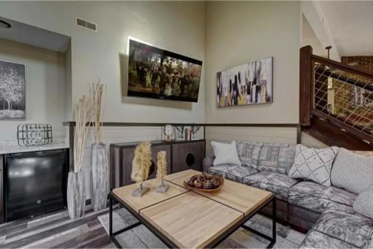 A comfortable living room featuring a plush sofa, a stylish coffee table, decorative plants, and artwork on the walls. The soft lighting and inviting arrangement create a warm, welcoming environment perfect for quiet moments, movie nights, or hosting guests.