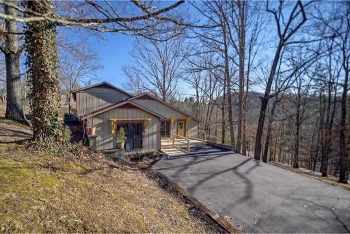 This image showcases a modern home exterior with a spacious wooden deck surrounded by lush trees. The deck is an inviting space for morning coffee or evening relaxation, and the architecture blends harmoniously with the natural landscape.